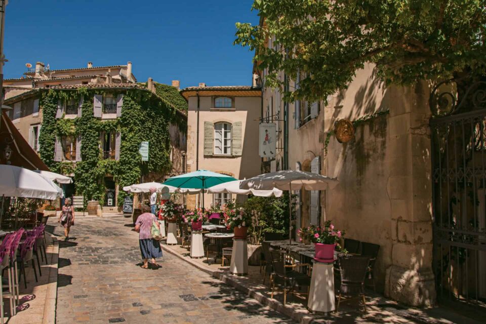 Ruelle fleurie typique de Lourmarin avec ses maisons en pierre et ses volets colorés